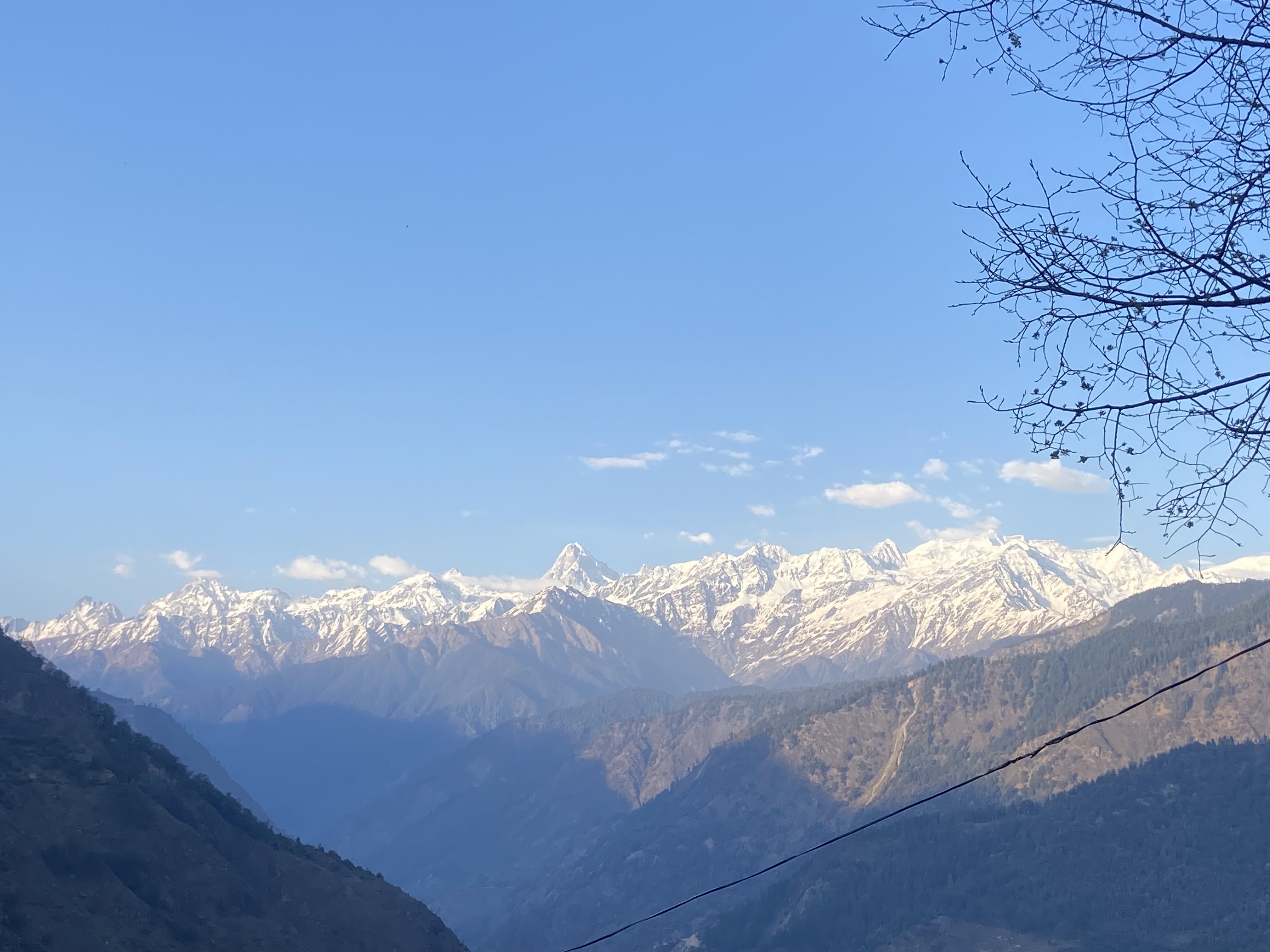 Snow-capped Garhwal peaks under a clear blue sky from Raithal